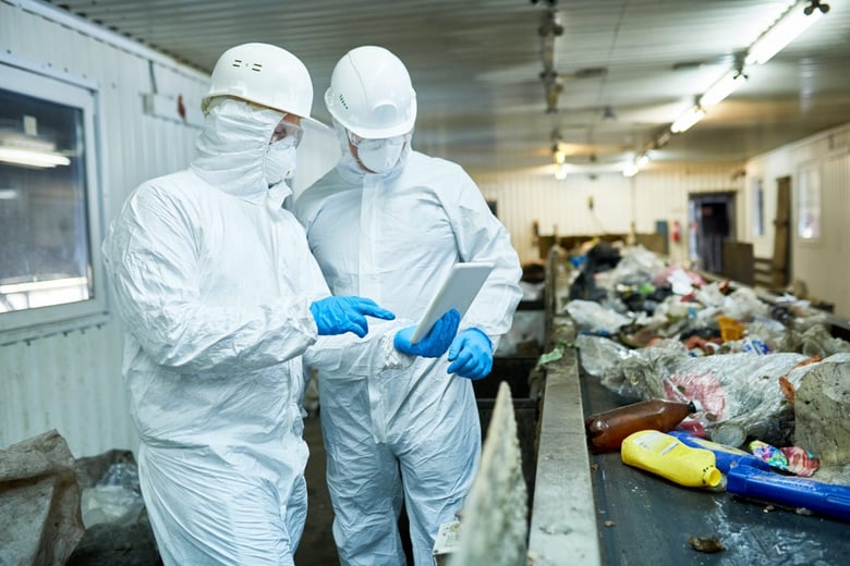 Two employees in protective suits at recycling centre